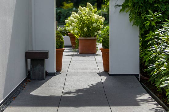 Auch hier im Seiteneingang zum Garten ist die schöne Wirkung des Naturstein-Bodenbelags im Gegenlicht zu erkennen.