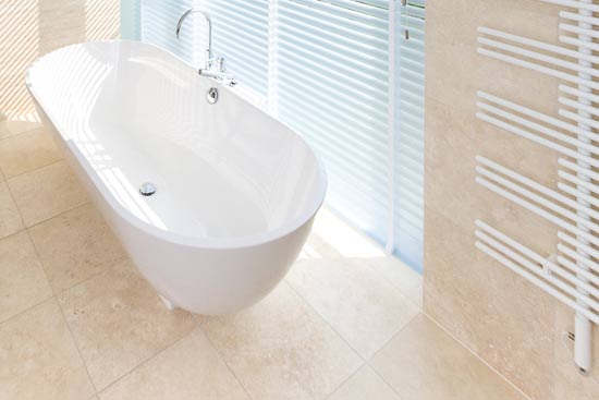 Badezimmer in Travertin Ivory. Durch das ganze Haus zieht sich der quadratische Bodenbelag. Er bietet eine schöne farbliche Ergänzung zu den weißen Sanitärobjekten.