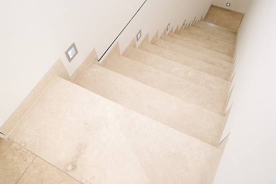 Eine Treppe mit hellem Naturstein. Den Belag der Treppe haben wir aus großformatigen Tafeln (sogenannten Unmaßtafeln) geschnitten.