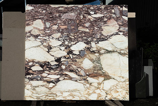 Calacatta Viola, gebürstet. Wie ein Schnitt durch eine Fels- und Gerölllawine bietet diese Naturstein-Unmaßtafel einen lebendigen Ausdruck in Tönen von beige bis zu einem dunklen Rotbraun.